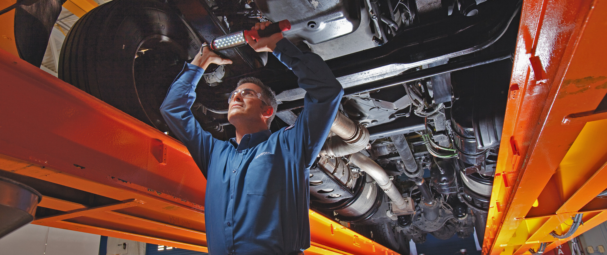 Kenworth technician inspecting truck underneath